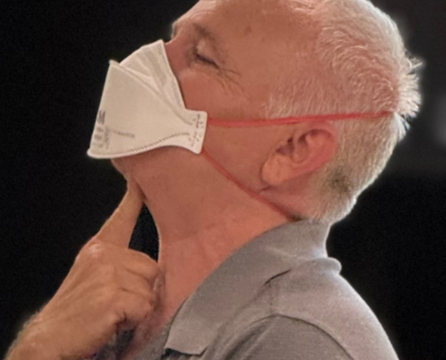 MaskFit+ instructor demonstrating where the bottom of the mask must be folded down and there cannot be any facial hair interrupting the seal.
